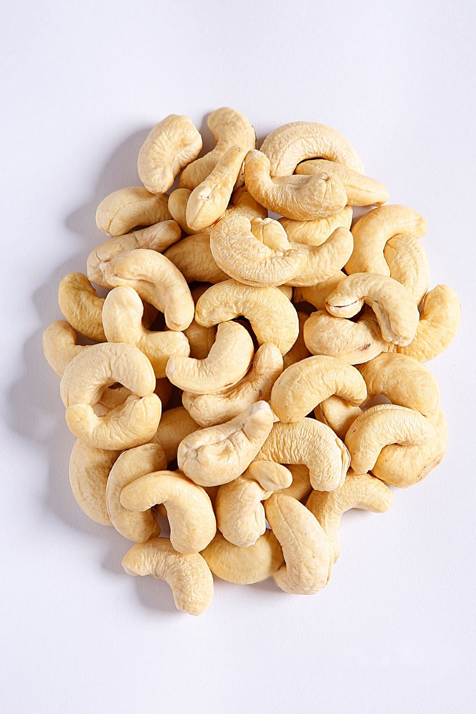 Whole white W-320 cashew kernels on a plain background